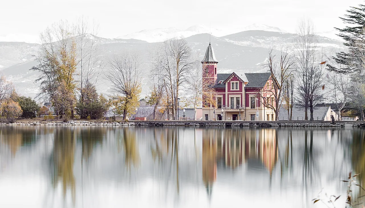 El estany de Puigcerdà en invierno, con las casas modernistas de la orilla y la sierra nevada al fondo