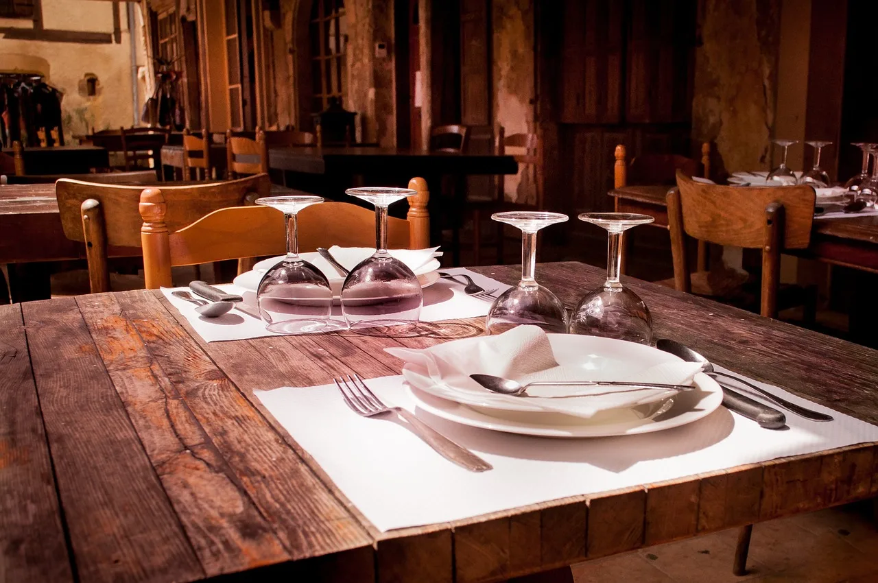 Mesa puesta con vasos y cubiertos en el comedor de madera de un restaurante de pueblo