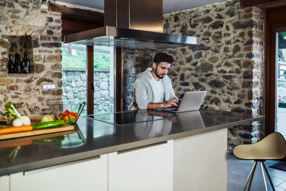 Autònom treballant amb l’ordinador portàtil a la cuina d’una casa de pedra de la Cerdanya